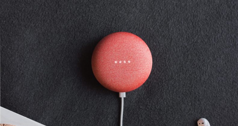 flat lay photography of coral Google Home Mini on black surface beside Apple AirPods
